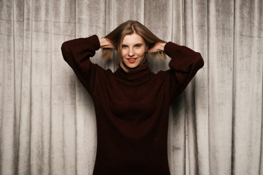 Studio portrait of a woman with long straight auburn hair and a turtleneck