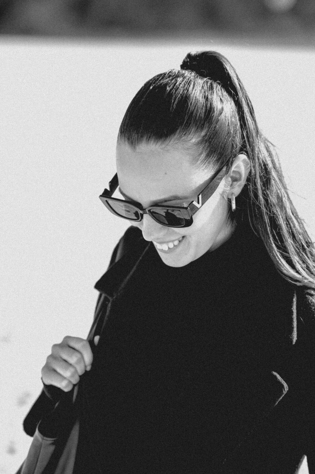 Studio portrait of a smiling woman with a ponytail and glasses