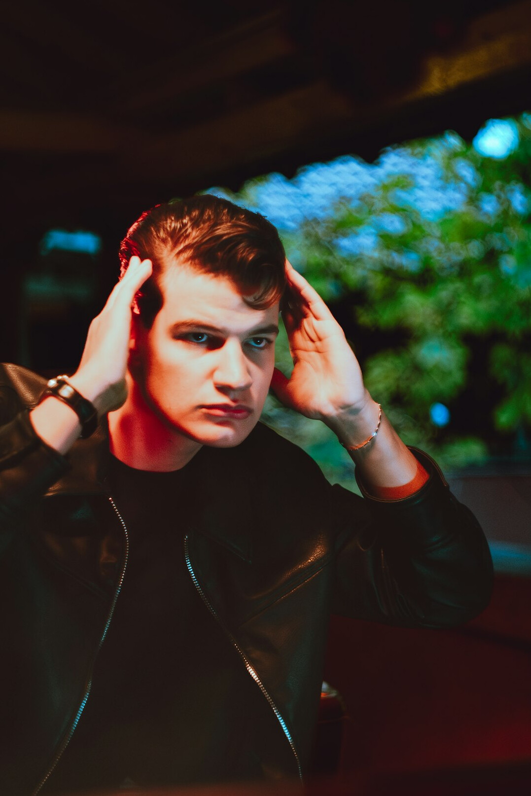 Studio portrait of a young man with short dark hair wearing headphones around the neck